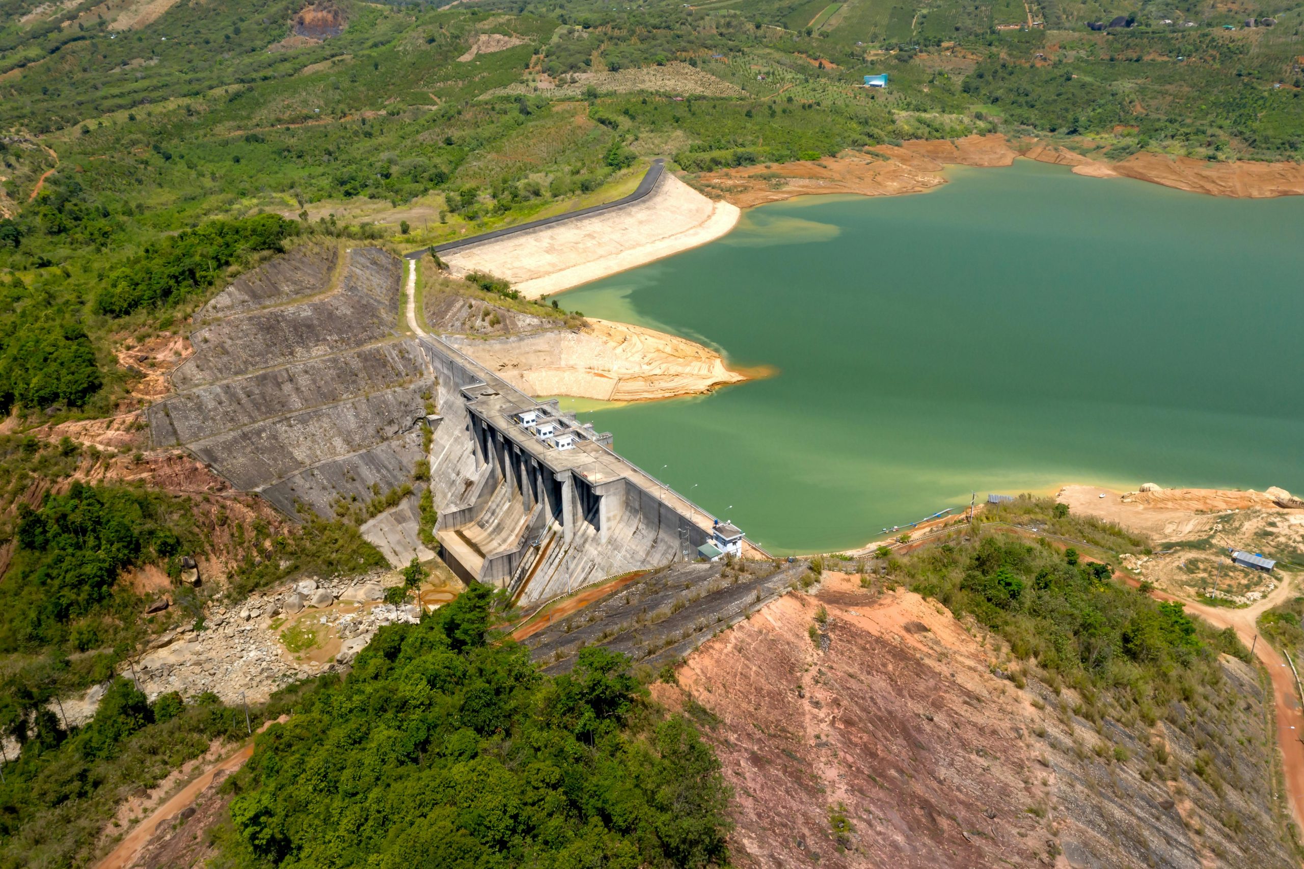 Stunning aerial view of a dam surrounded by lush green landscape and serene reservoir.