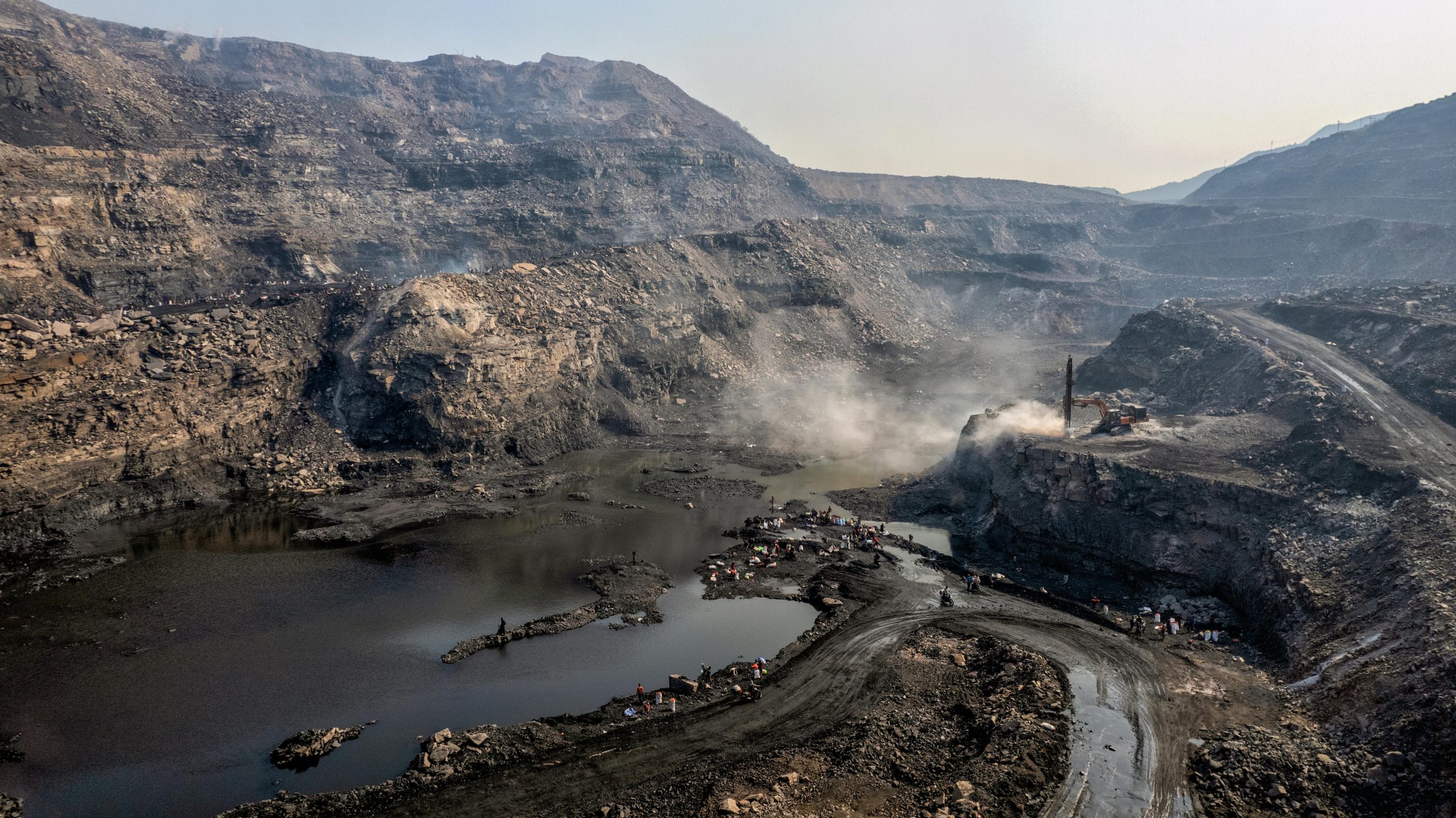 A dramatic aerial view of a coal mine in Dhanbad, Jharkhand, India showcasing rugged landscapes and mining activity.